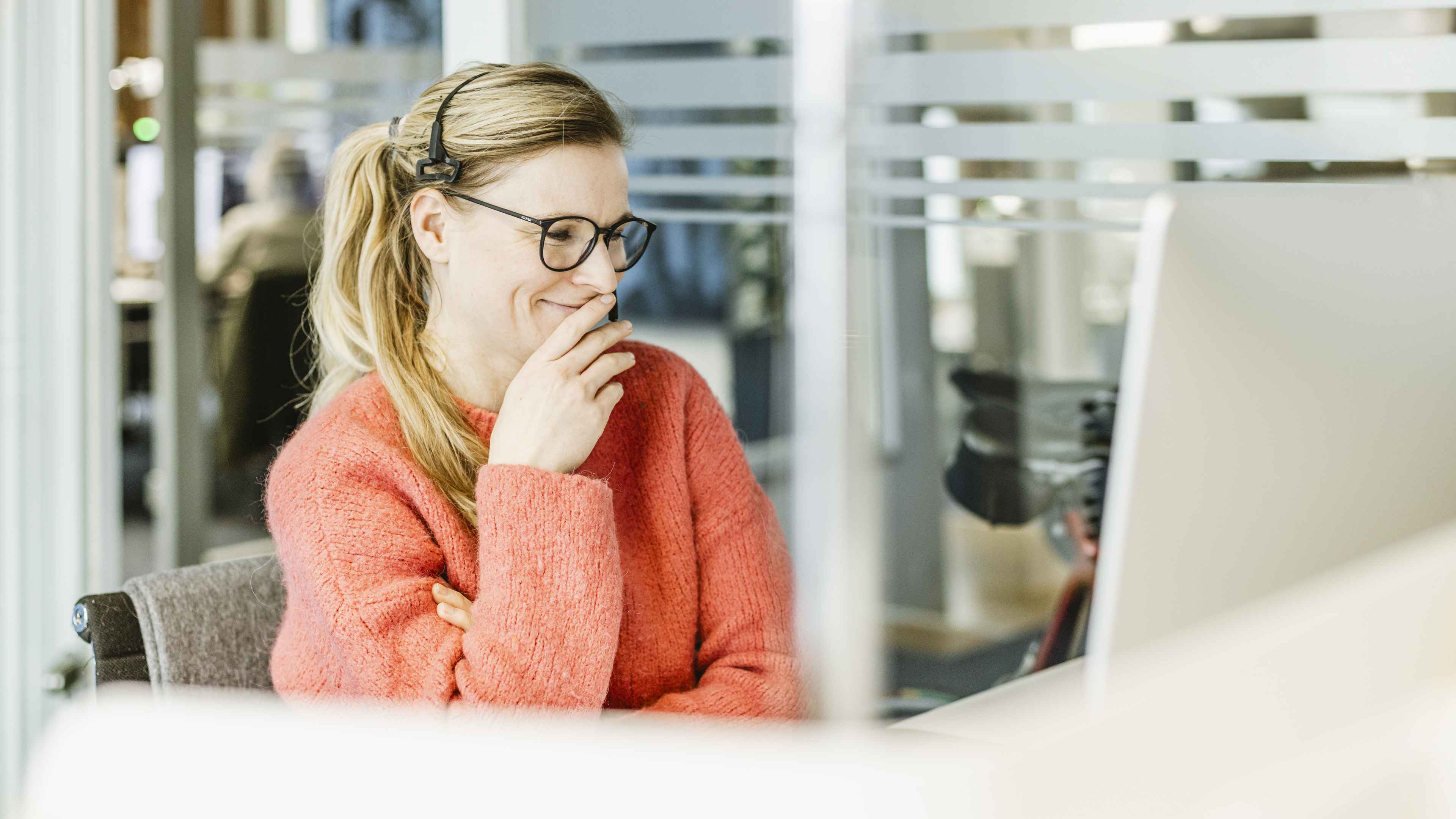Unsere Kollegin Regina Schmidt befindet sich in einem digitalen Meeting und sitzt schmunzelnd vor ihrem Bildschirm.