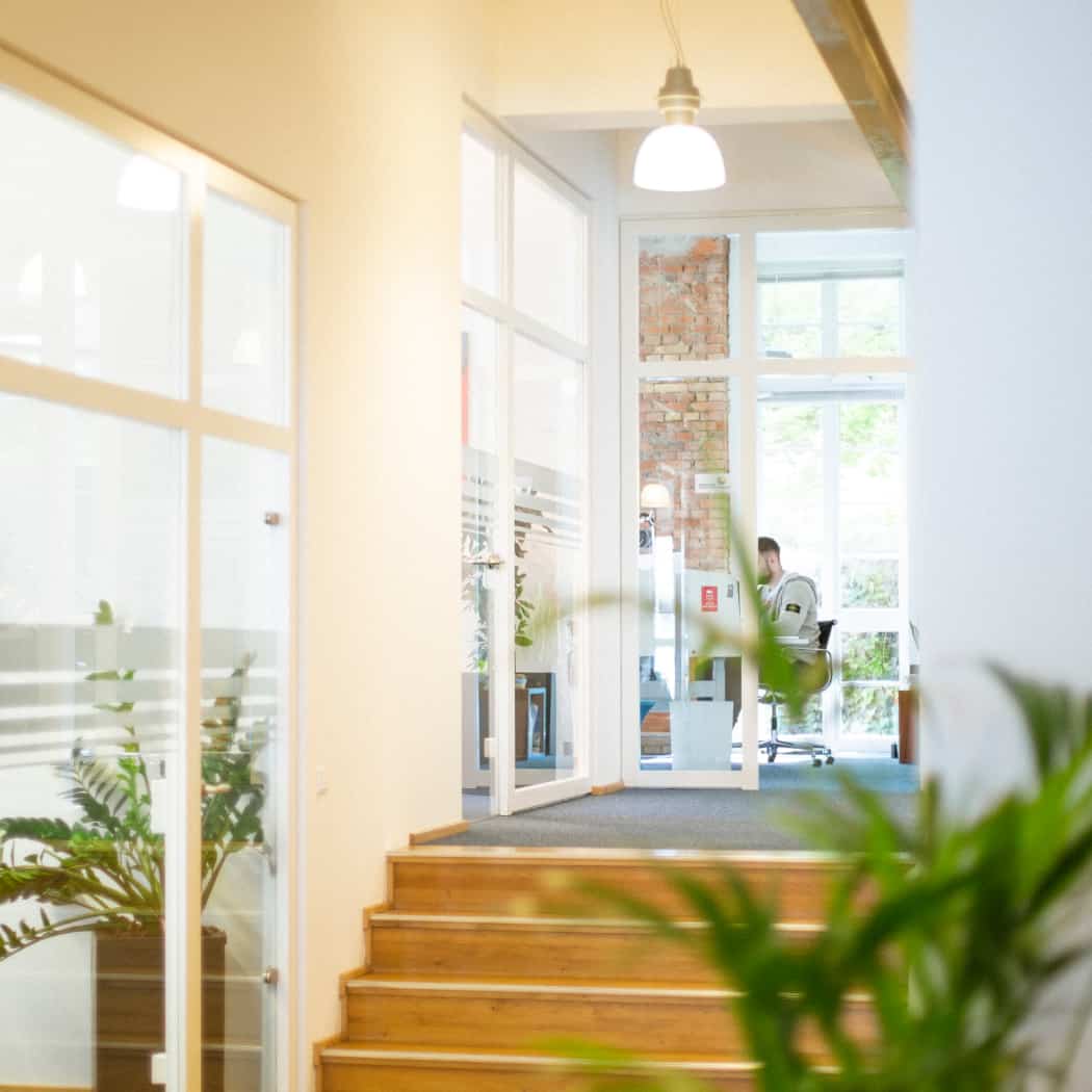 hochzwei_wir_teaser_07.jpg Blick durch den Flur mit Pflanzen auf die Holztreppe