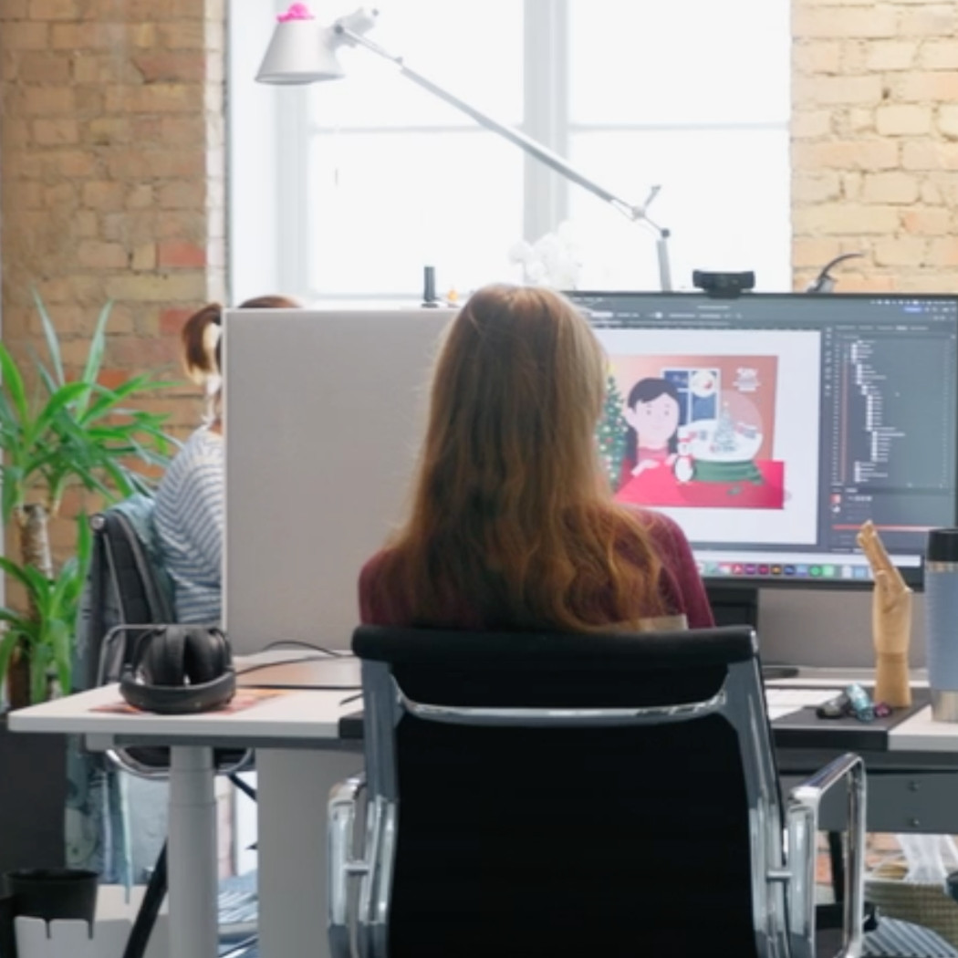 Eine Frau arbeitet am Computer in einem Großraumbüro