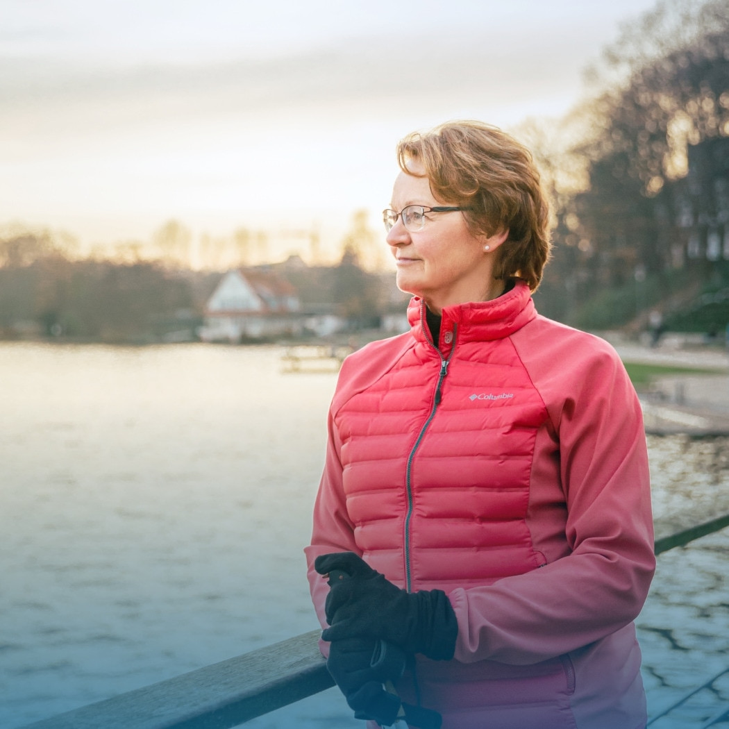hochzwei_wksrecruiting_teaser_06.jpg Eine Frau in einer pinken Jacke steht an einem Geländer