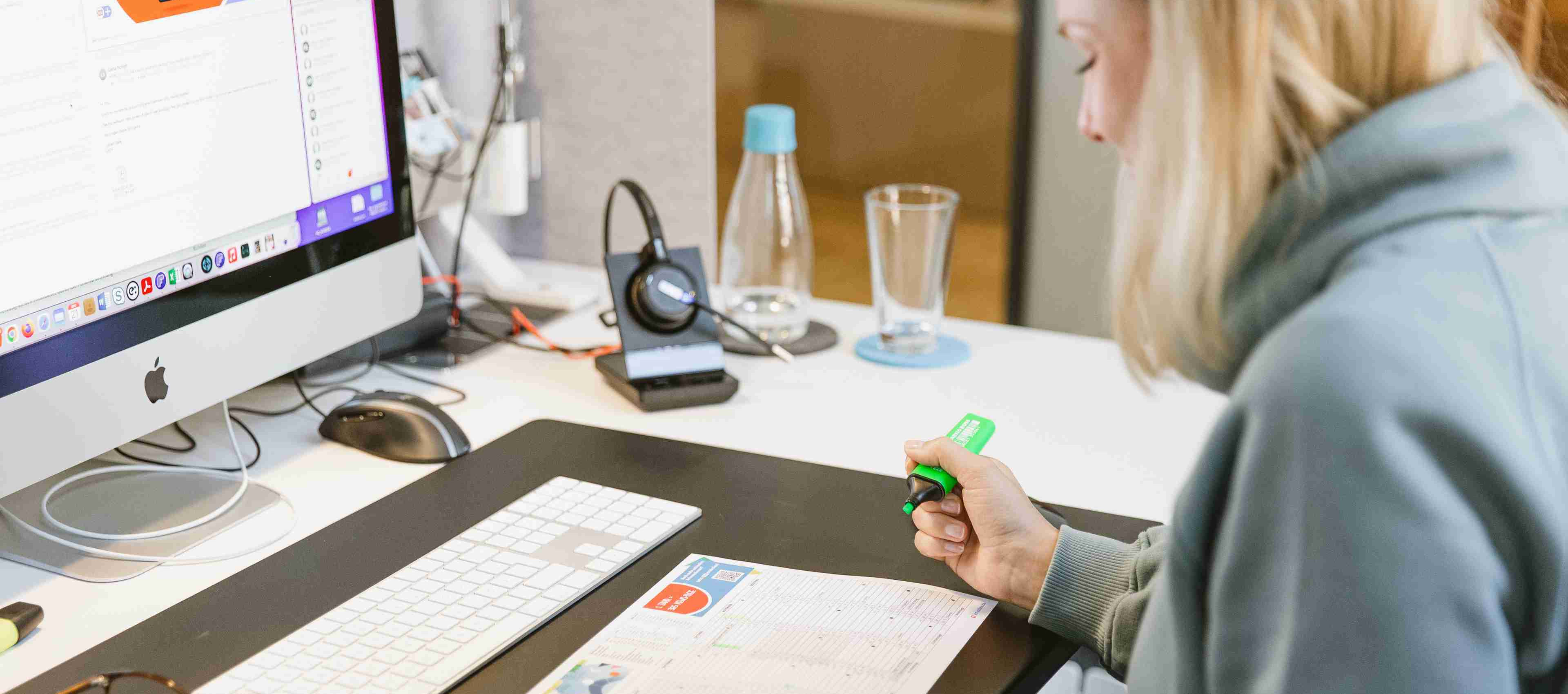 Blonde Frau arbeitet konzentriert am Schreibtisch