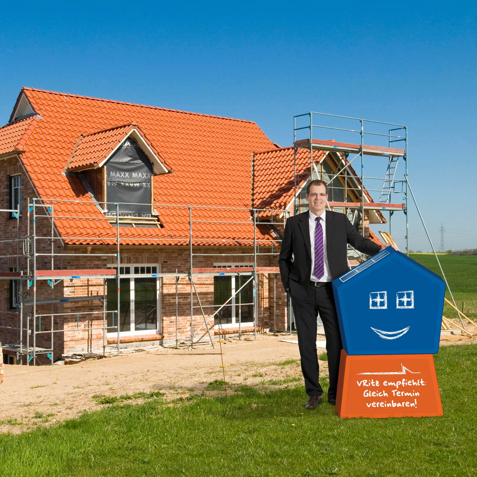 hochzwei_vrb_teaser_06.jpg Mann im Anzug steht vor einem Neubau Haus