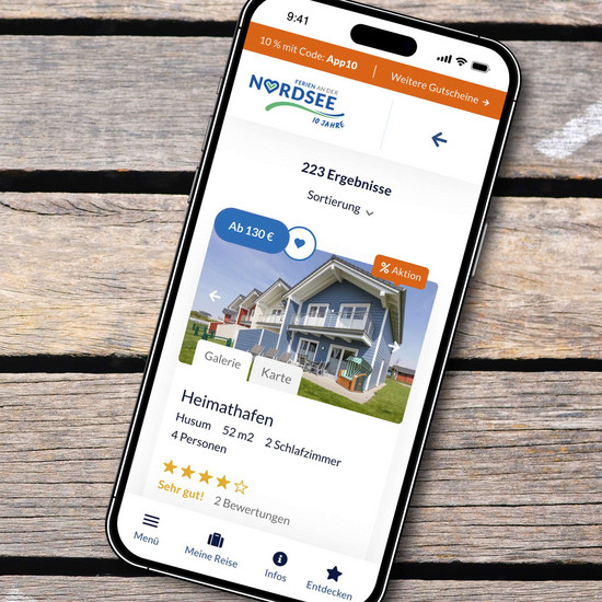 5 Tipps zur Gästegewinnung und -bindung Smartphone mit Startseite einer Ferienvermietung vor Holzhintergrund