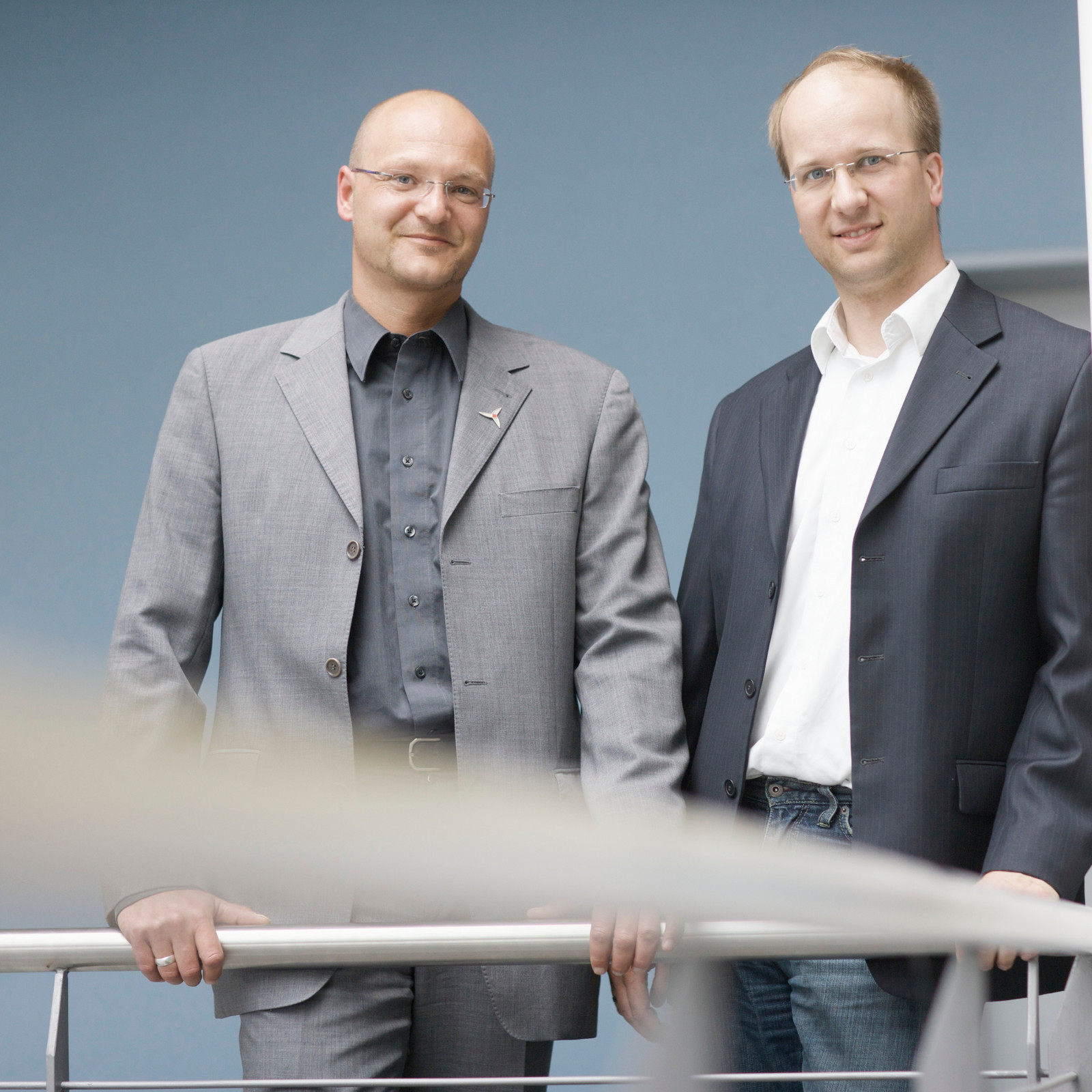 Zwei Männer im Anzug lächeln in die Kamera