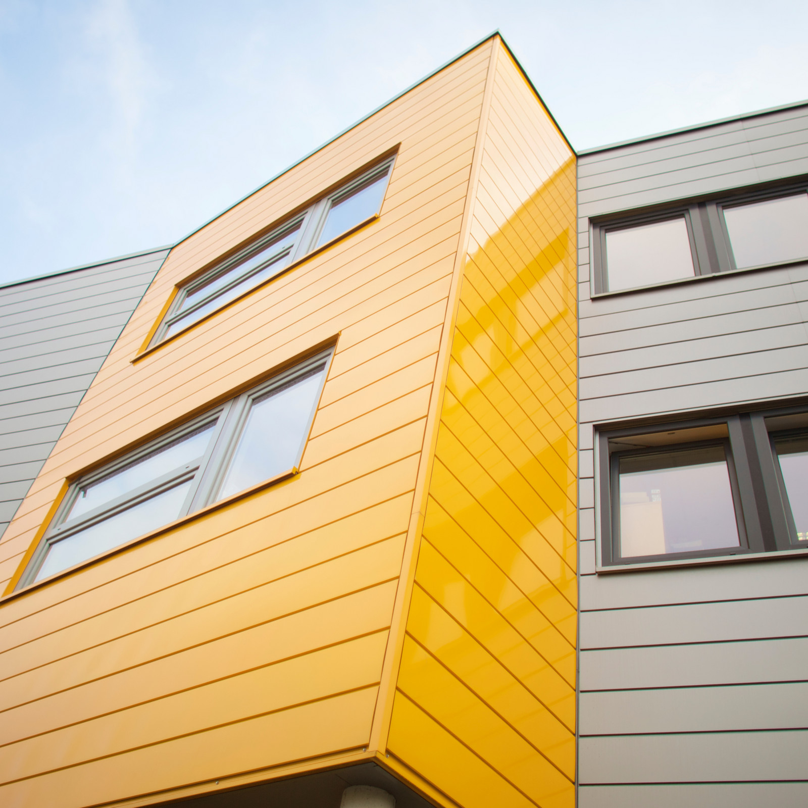 hochzwei_greylogix_teaser_07.jpg Graues Gebäude mit einer Orangenen Fassade