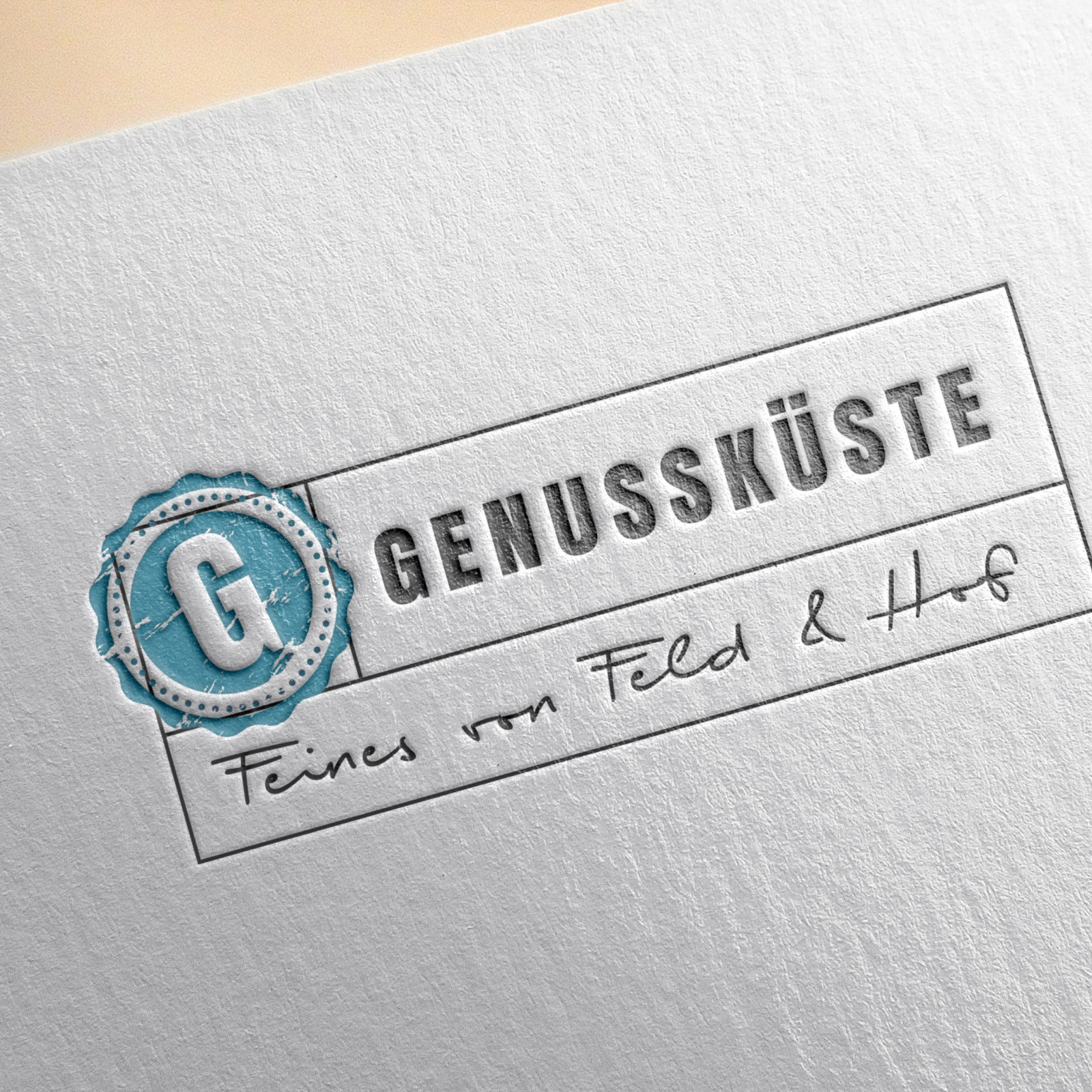 hochzwei_kogu_teaser_02_hauptteaser.jpg Das Logo von Genüssküste eingestampft auf weißem Papier