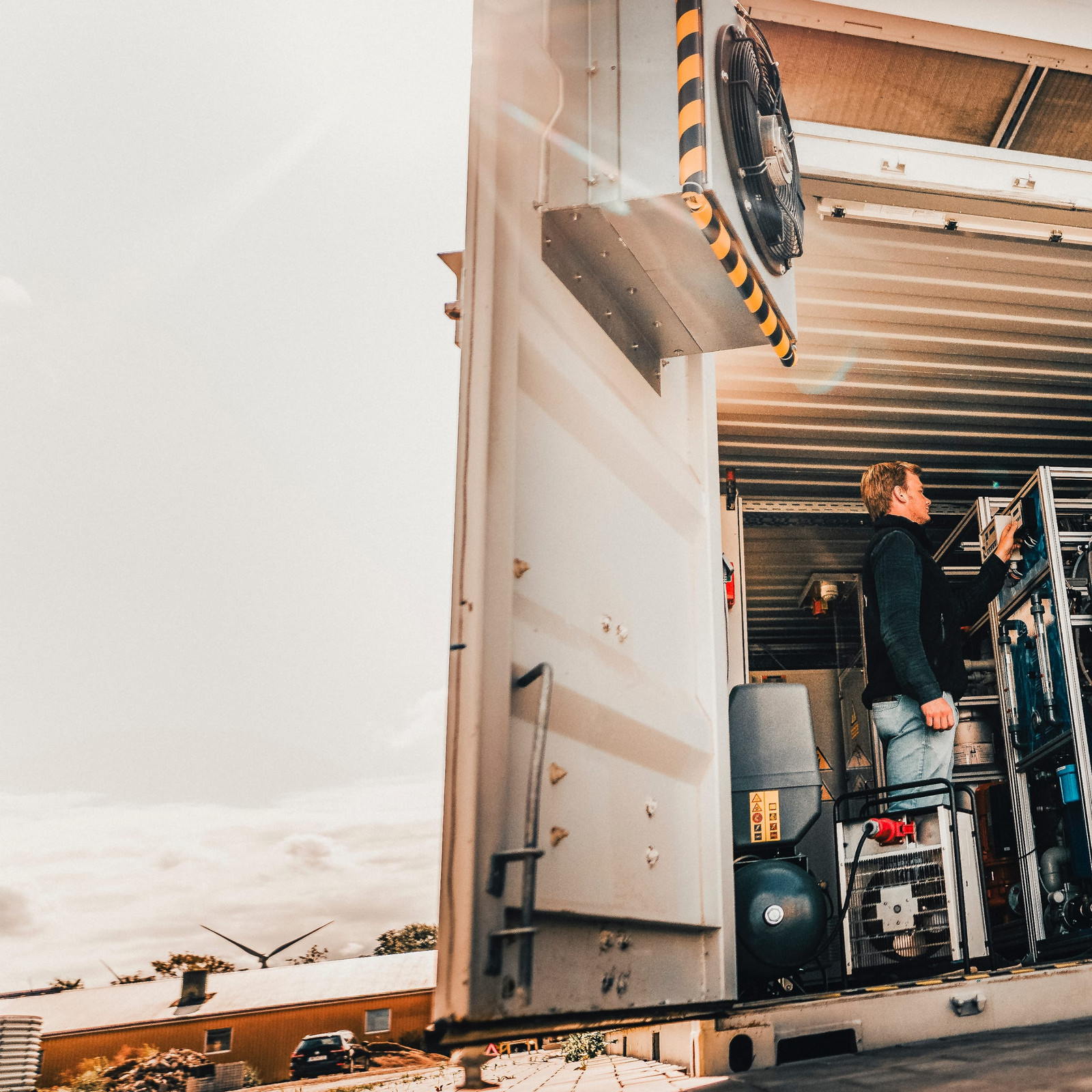 hochzwei_gp_teaser_07.jpg Ein Mann steht in einem Container und schraubt an einer Maschine