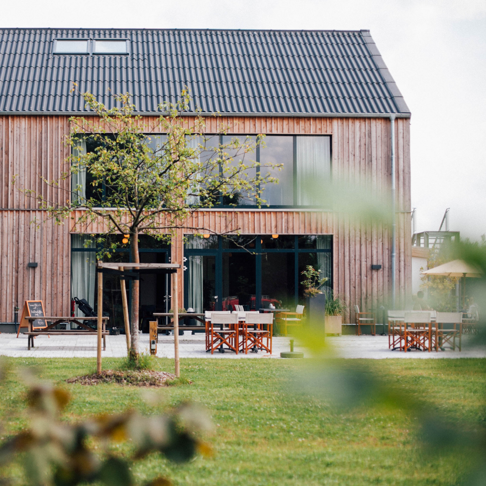 hochzwei_roba_teaser_06.jpg Blick vom Garten auf den zweistöckigen Neubau aus Holz mit bodentiefen Fenstern