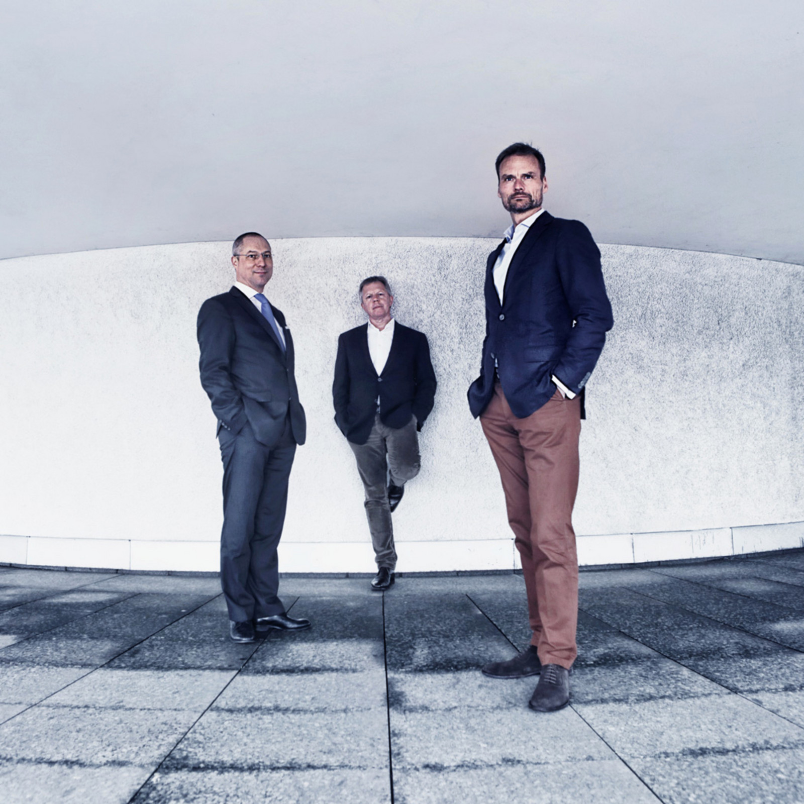 hochzwei_conreri_teaser_03.jpg Drei Männer im Anzug mit den Händen in den Taschen