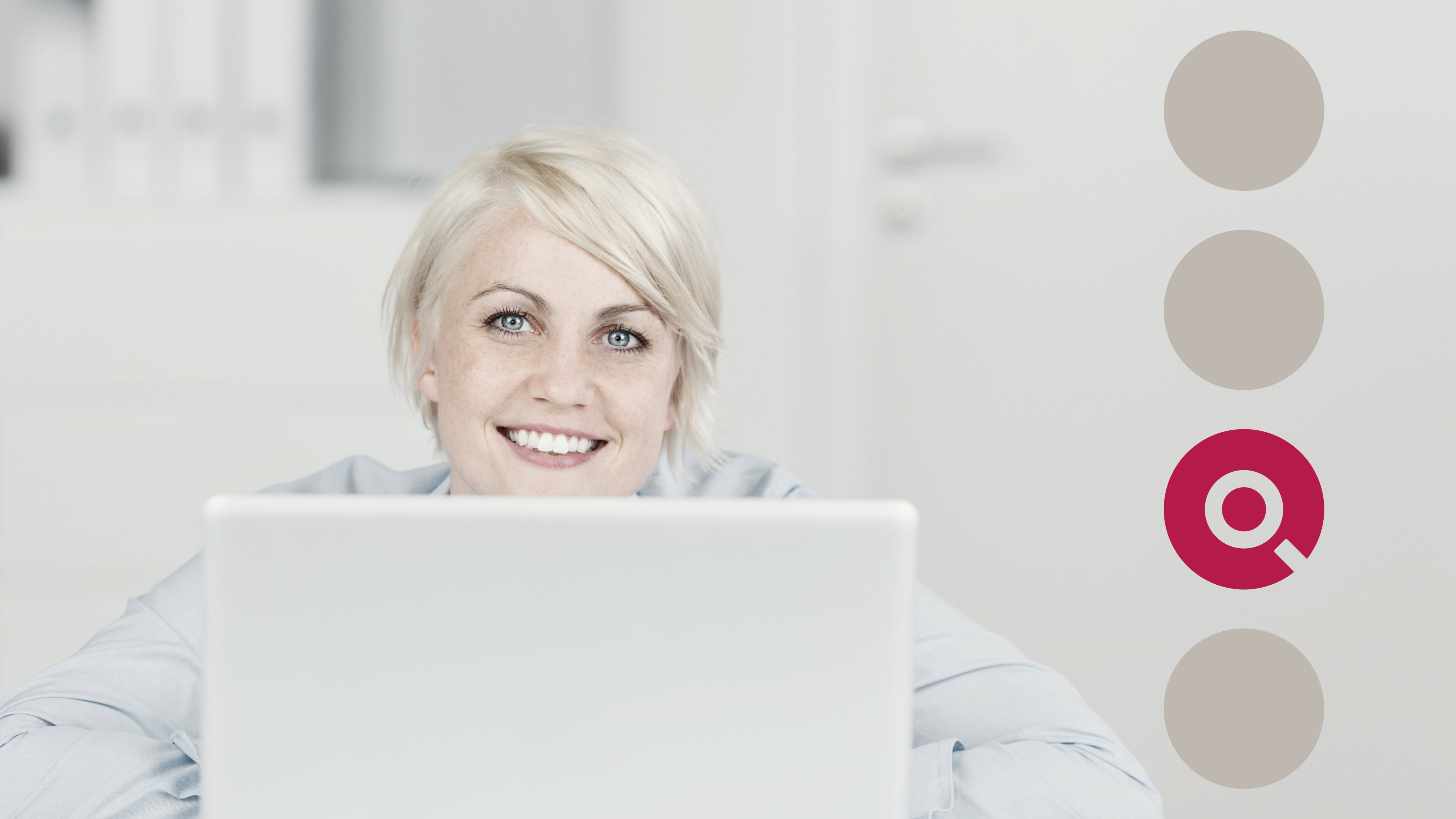 Blonde Frau sitzt am Computer und schaut in die Kamera