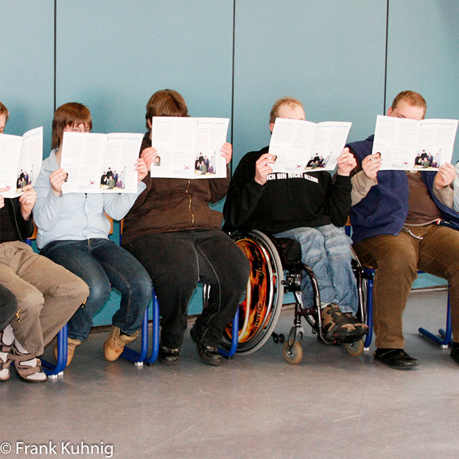 hochzwei_muer_teaser_03.jpg Fünf Personen sitzen und halten sich weiße Zettel vor das Gesicht