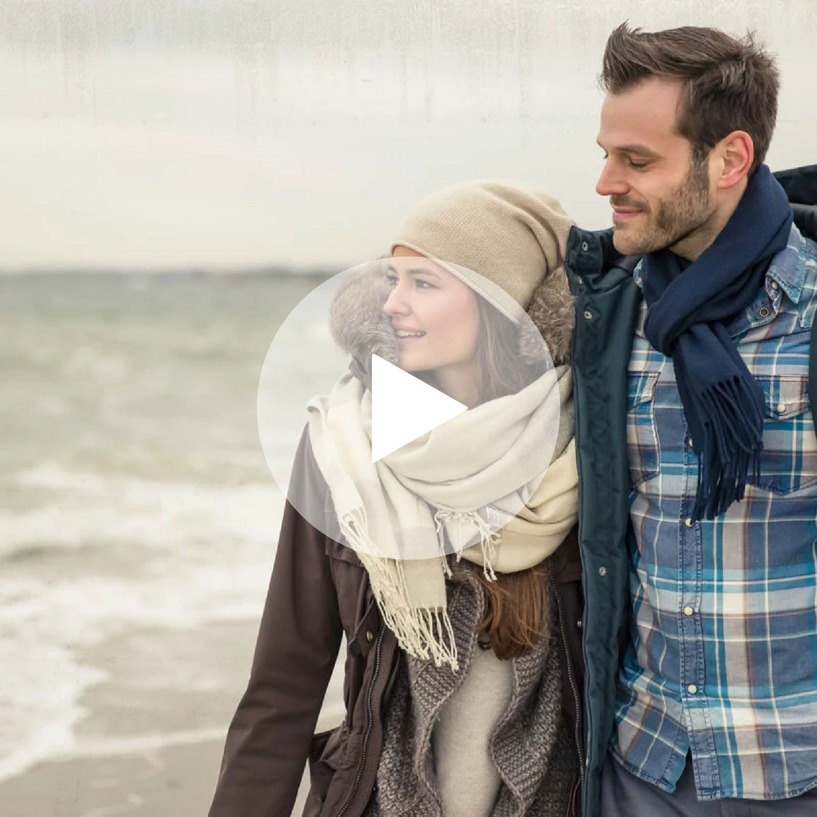 Pärchen geht Arm in Arm am Strand spazieren