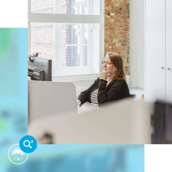 Arbeitsbelastung HOCHZWEI-Mitarbeiterin schmunzelnd am Arbeitsplatz