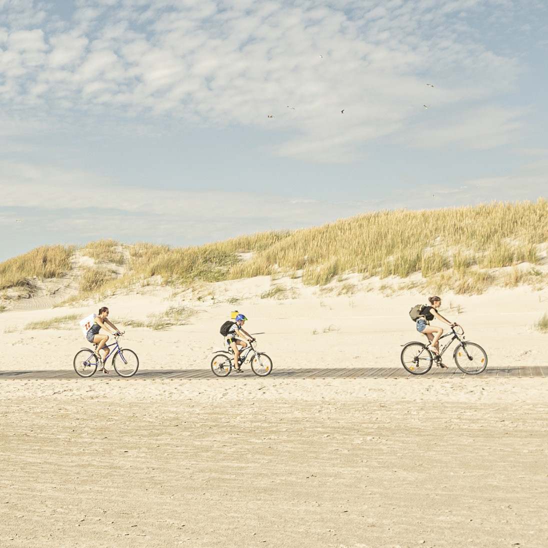Drei Fahrradfahrer in der Ferne am Strand