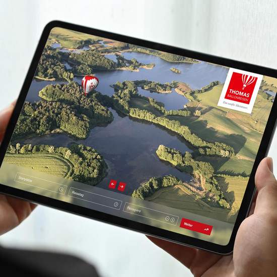 Tablet mit der Webseite von Thomas Ballonreisen, die eine Luftaufnahme einer Seenlandschaft zeigt