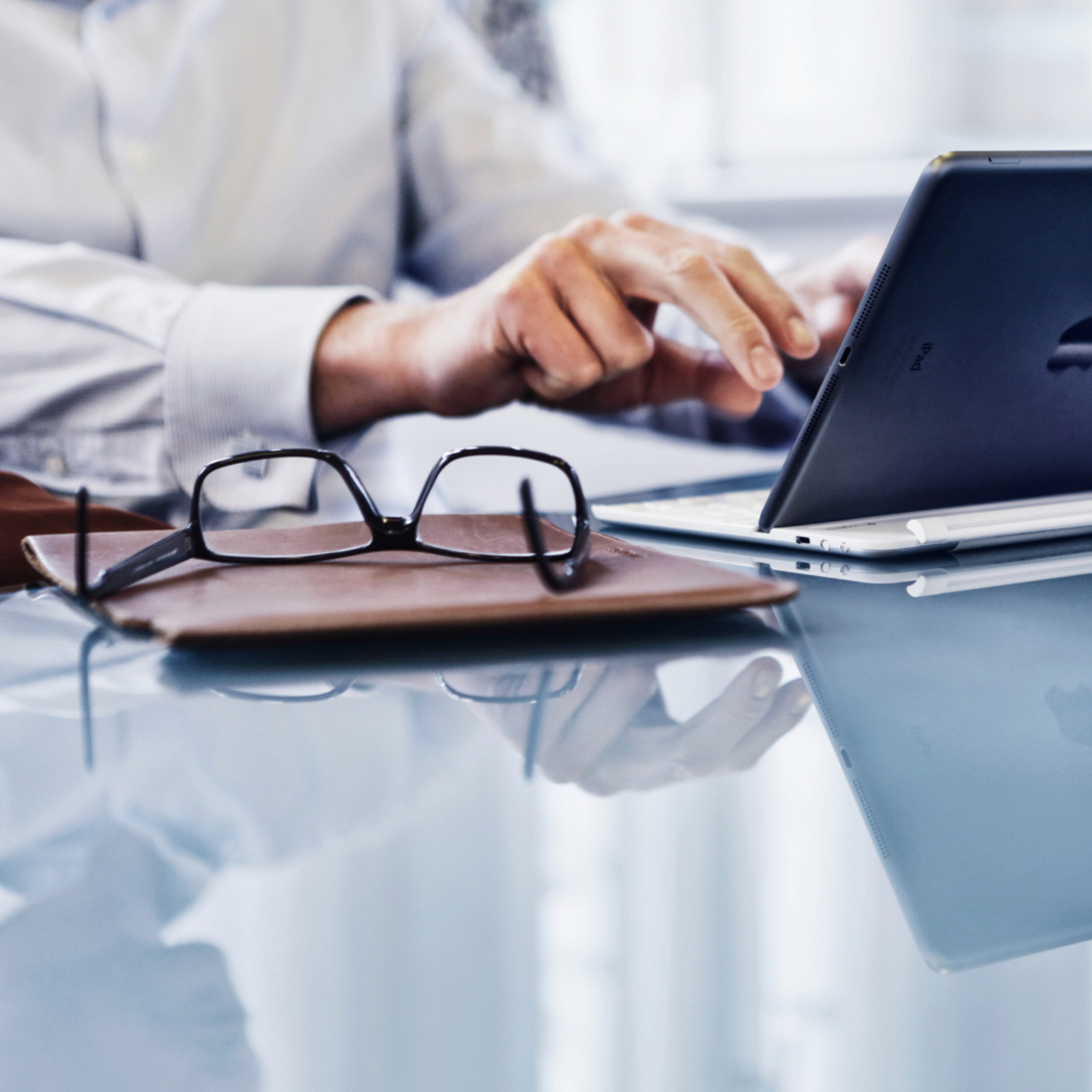 hochzwei_conreri_teaser_04.jpg Brille und Mappe auf dem Tisch neben einer Person am Laptop