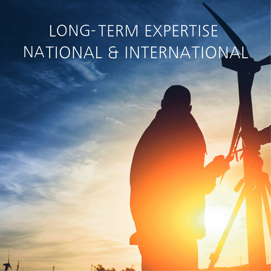 Person zwischen Windräder bei Sonnenuntergang