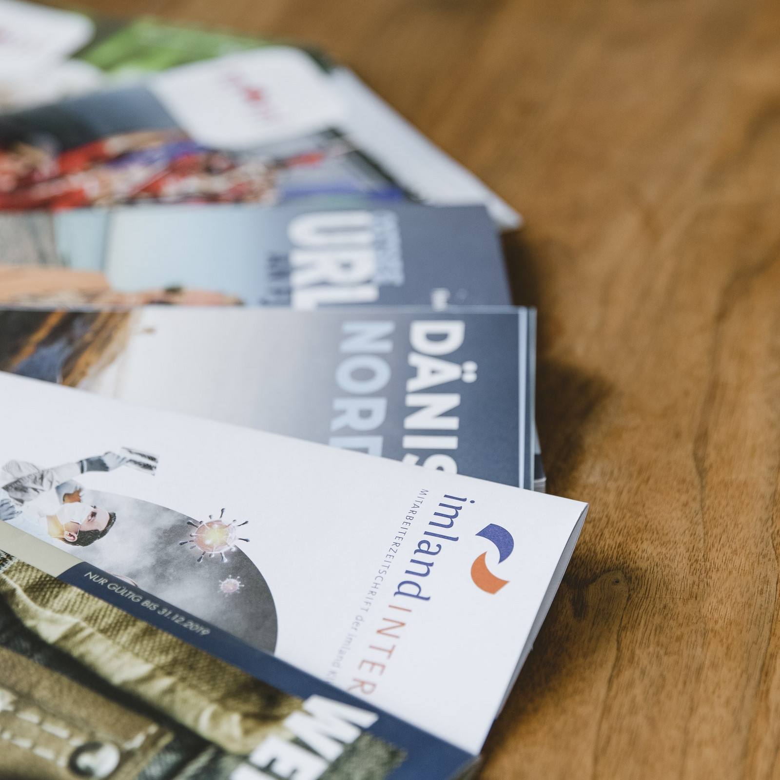 Aufgefächerte Flyer liegen auf einem Holztisch