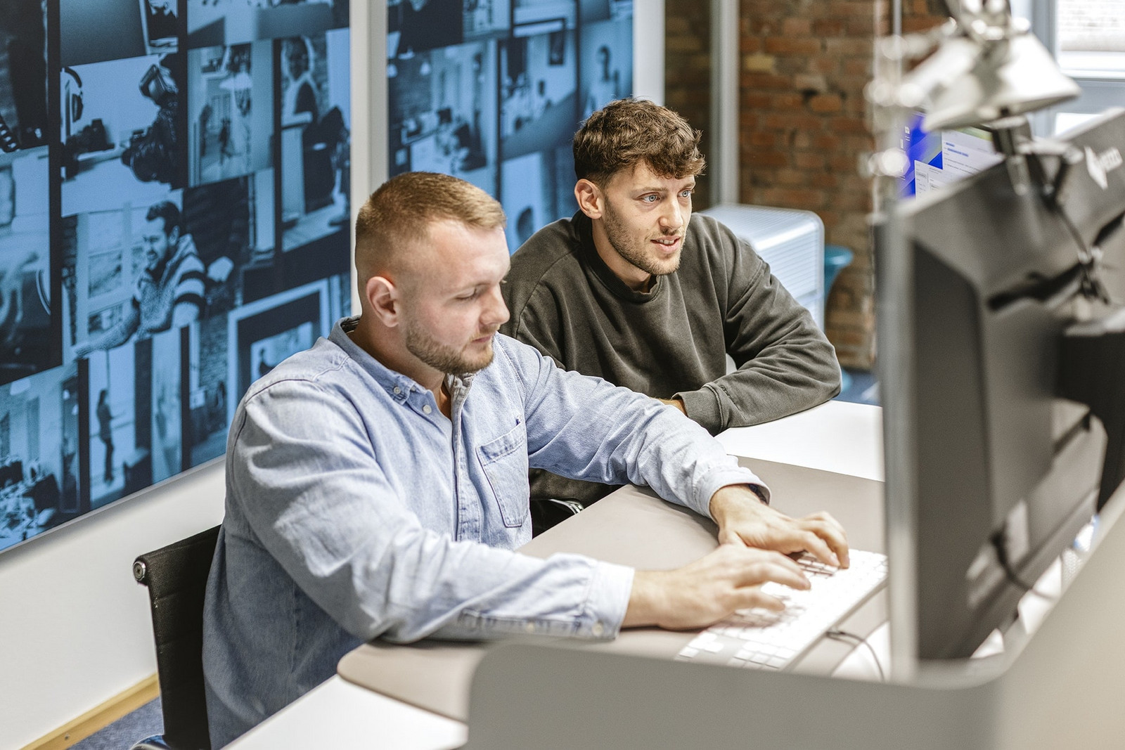 Zwei Mitarbeiter von HOCHZWEI blicken gemeinsam auf einen PC