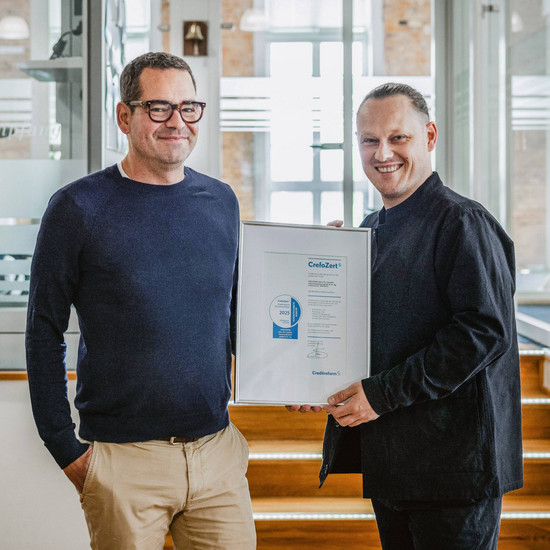 Geschäftsführer Felix Worm posiert mit dem Herrn von CrefoZert im Büro in Flensburg