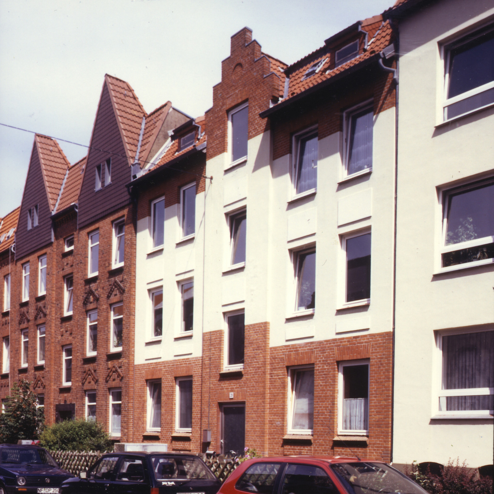 hochzwei_fab_teaser_08.jpg Dreistöckige Wohnhäuser und davor parkende Autos