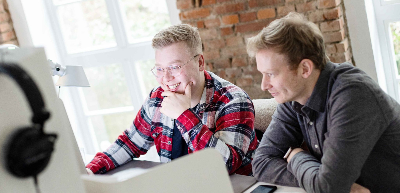 Zwei Mitarbeiter von Hochzwei schauen sich etwas gemeinsam an einem PC an.