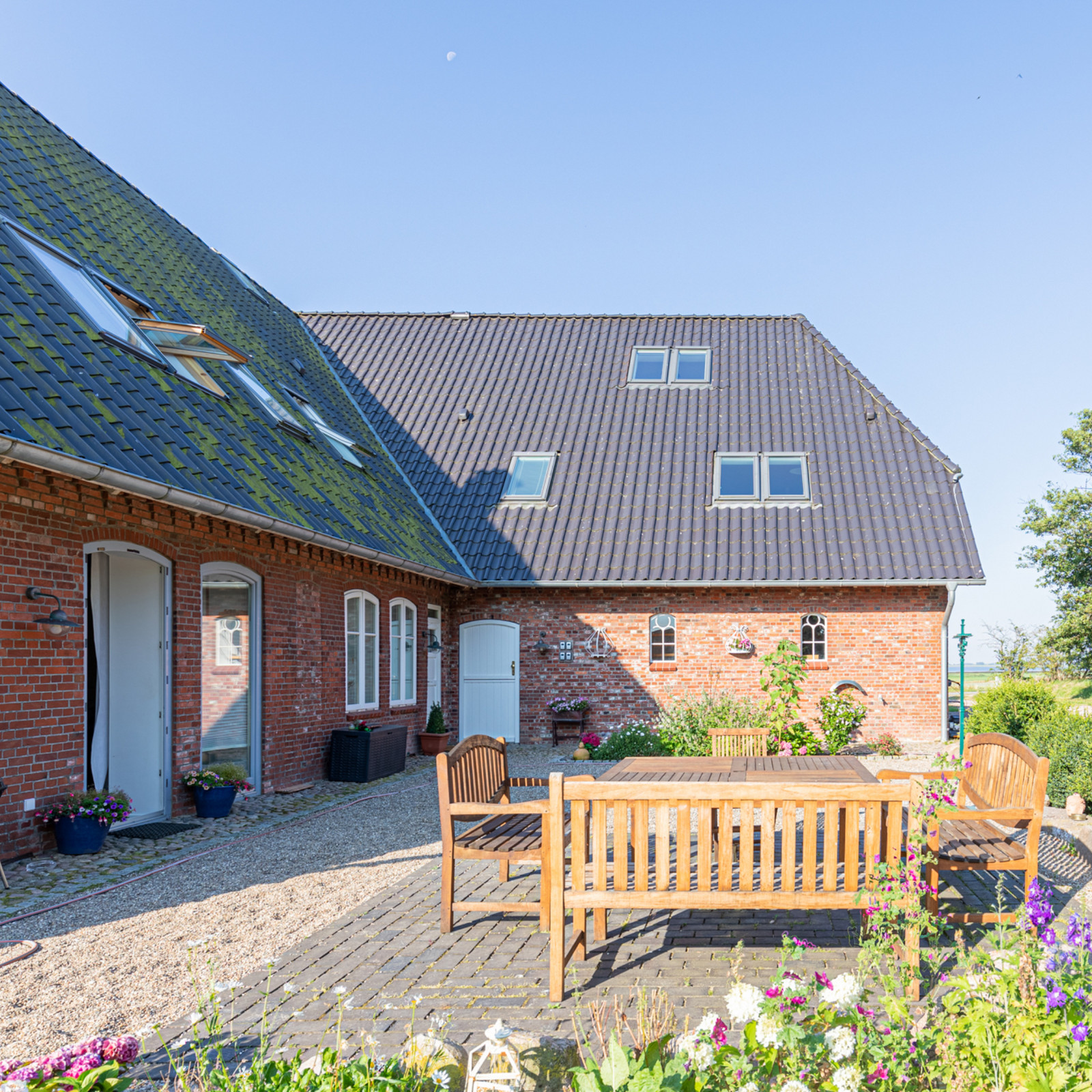 hochzwei_feano_teaser_03.jpg Holzmöbel auf Terrasse vor Klinkerhaus