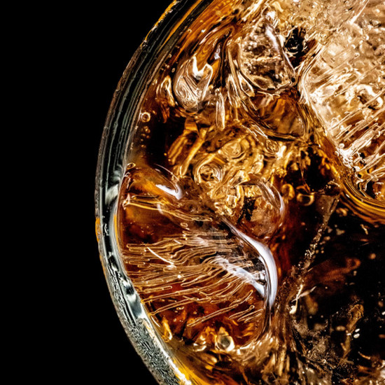 Nahaufnahme von einem Glas mit Whiskey mit Eiswürfeln