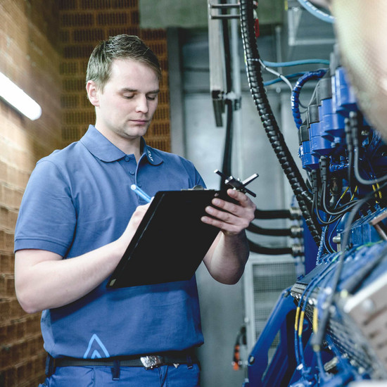 Feldfrisch Mitarbeiter im Polohemd steht an Maschine und schaut auf Klemmbrett in der Hand